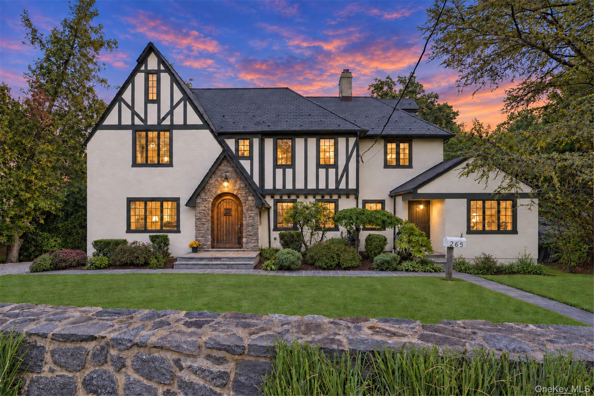Behind its handsome stone wall, a grand Tudor of unmistakable characte...